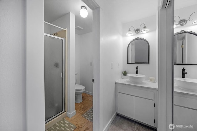 full bathroom featuring a stall shower, baseboards, vanity, and toilet