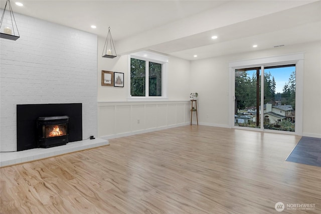 unfurnished living room featuring light wood-type flooring, a brick fireplace, and recessed lighting