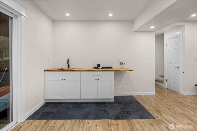 bar featuring recessed lighting, baseboards, a sink, and wood finished floors