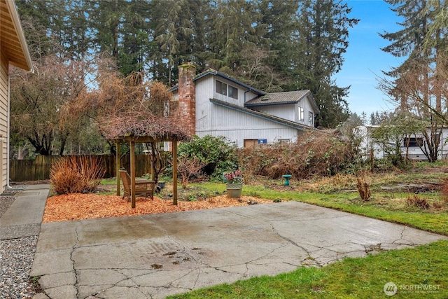 view of property exterior featuring a patio area, fence, and a chimney