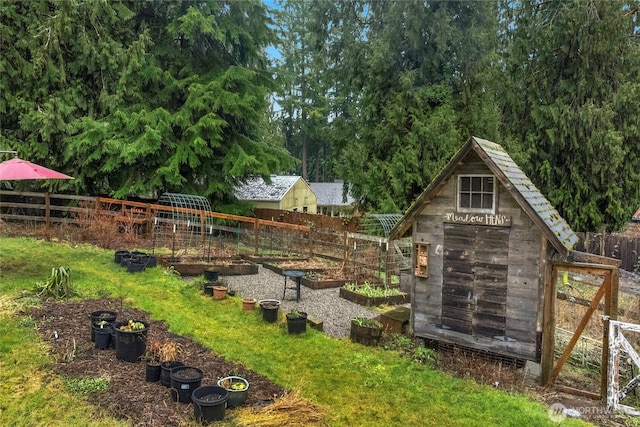 view of yard featuring a garden, fence, and an outdoor structure