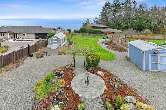 view of yard with a garden, a fenced backyard, a storage unit, and an outbuilding