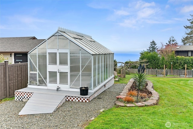 view of greenhouse with a fenced backyard and a lawn