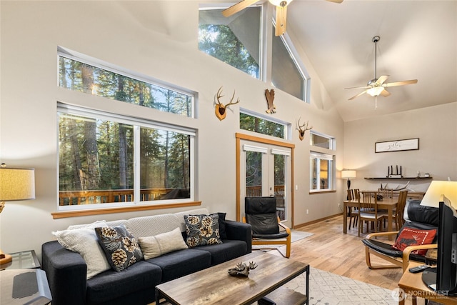 living area featuring light wood-style floors, a healthy amount of sunlight, and a ceiling fan