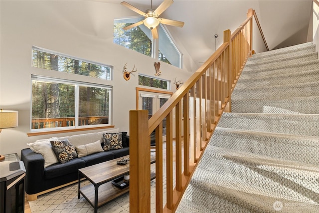 staircase with a high ceiling and a ceiling fan