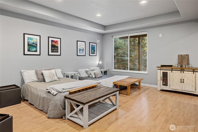 bedroom featuring light wood-type flooring, baseboards, a raised ceiling, and recessed lighting