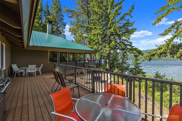 wooden terrace featuring outdoor dining space and a water view