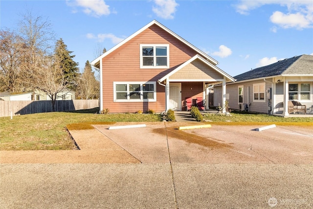 view of front of home with uncovered parking, a patio area, fence, and a front lawn