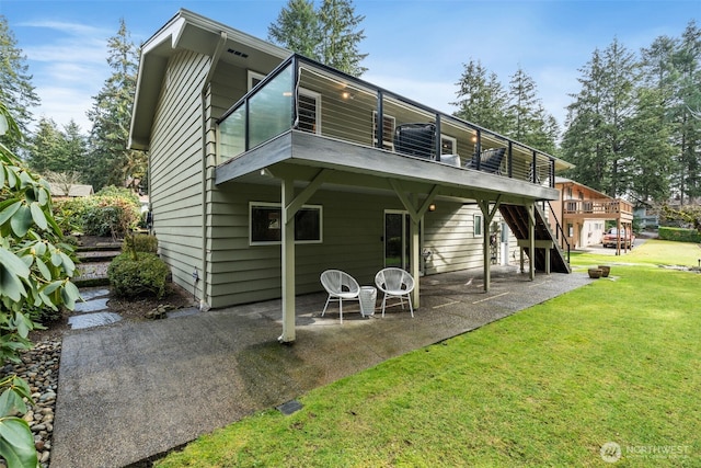 rear view of property featuring a patio, stairway, and a lawn