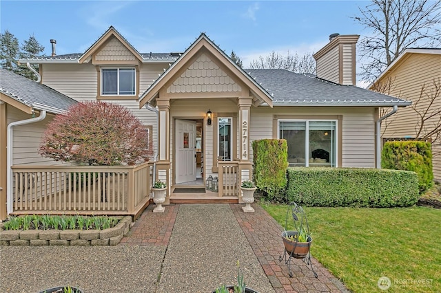 view of front of property with a shingled roof, a chimney, and a front yard