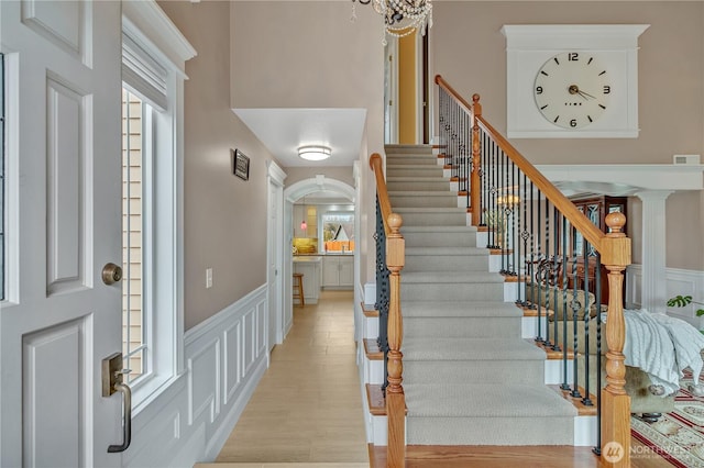 entrance foyer with visible vents, a decorative wall, stairway, wainscoting, and light wood-type flooring