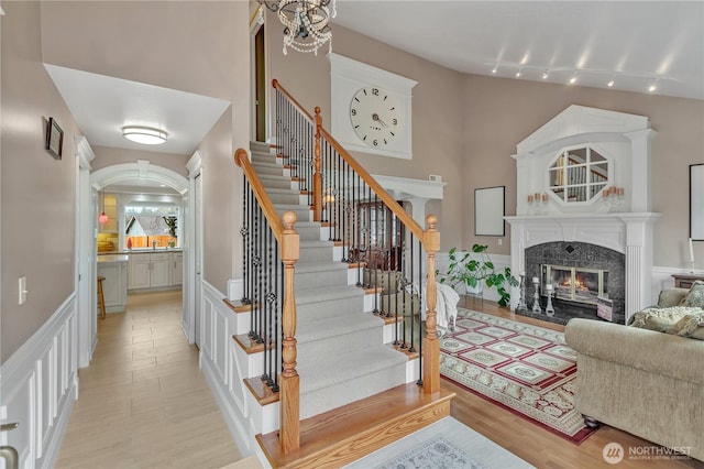 entrance foyer with light wood-type flooring, stairway, and a high end fireplace