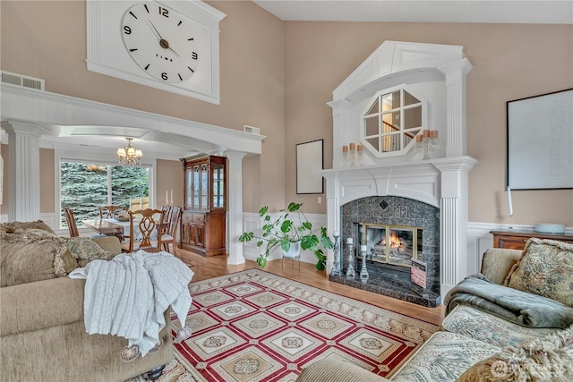 living area with decorative columns, visible vents, a premium fireplace, wainscoting, and wood finished floors