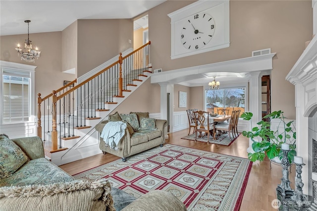 living area featuring wood finished floors, visible vents, stairway, and an inviting chandelier