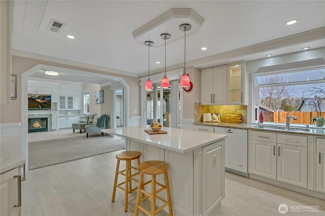 kitchen with dishwasher, a wainscoted wall, a sink, and visible vents