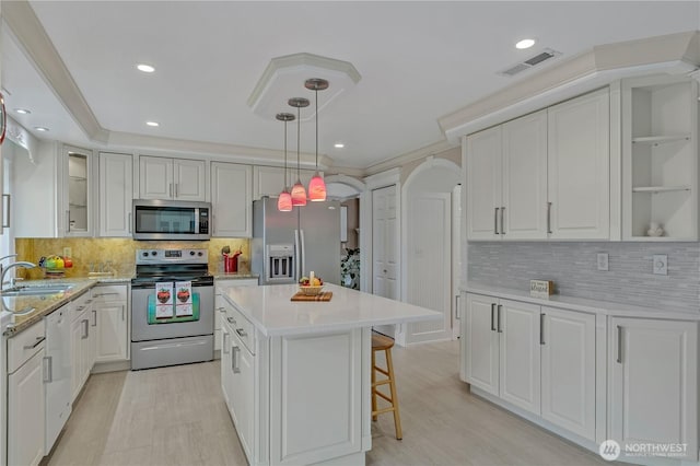 kitchen featuring arched walkways, stainless steel appliances, a sink, visible vents, and white cabinetry