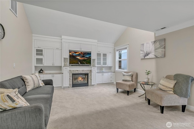 living room with light carpet, visible vents, vaulted ceiling, and a high end fireplace