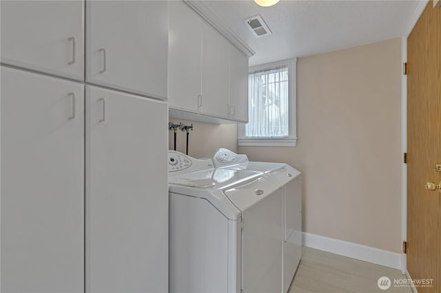 laundry room featuring a textured ceiling, visible vents, baseboards, cabinet space, and washing machine and clothes dryer