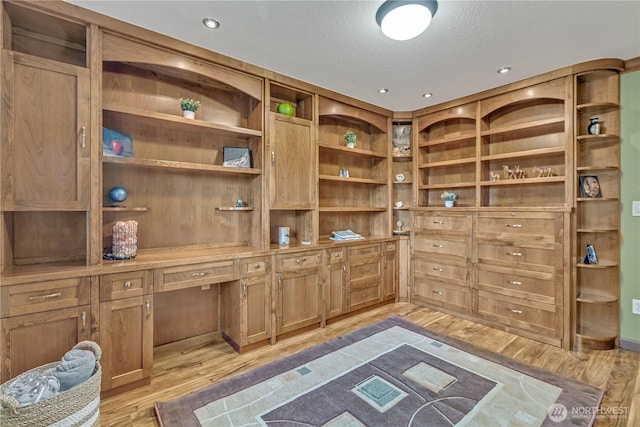 office featuring light wood-style floors, built in desk, and a textured ceiling