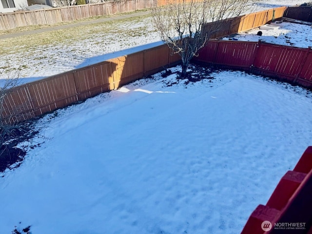 yard layered in snow featuring a fenced backyard