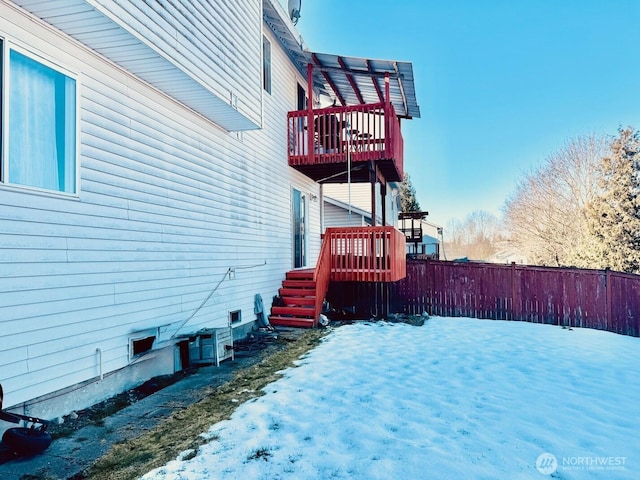 snow covered property with a deck and fence