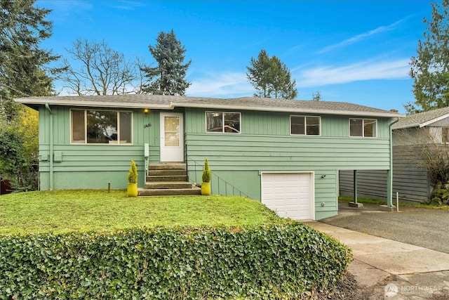 view of front of home with driveway, an attached garage, a front lawn, and entry steps