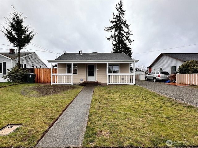 view of front of property with covered porch, a front yard, and fence