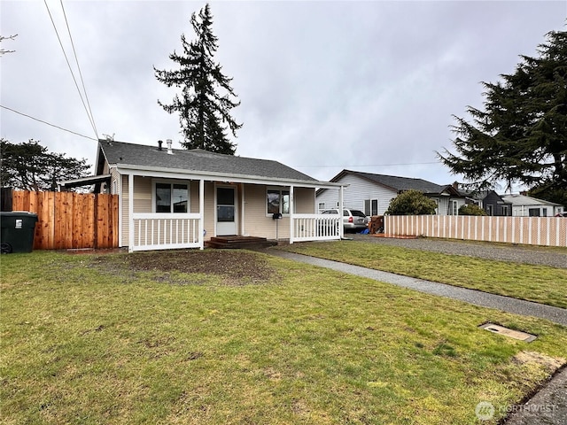 view of front of home featuring covered porch, a front lawn, and fence