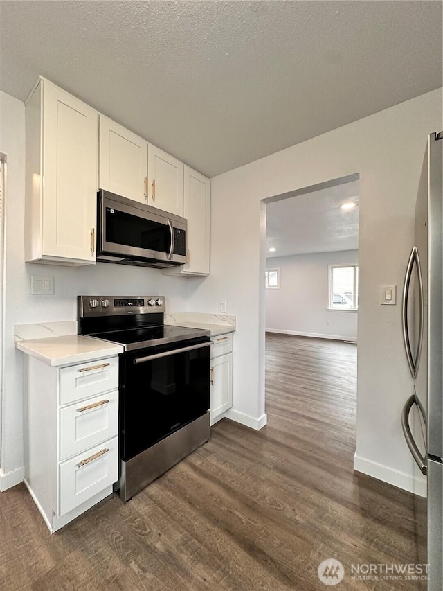 kitchen featuring stainless steel appliances, dark wood-style flooring, white cabinetry, baseboards, and light countertops