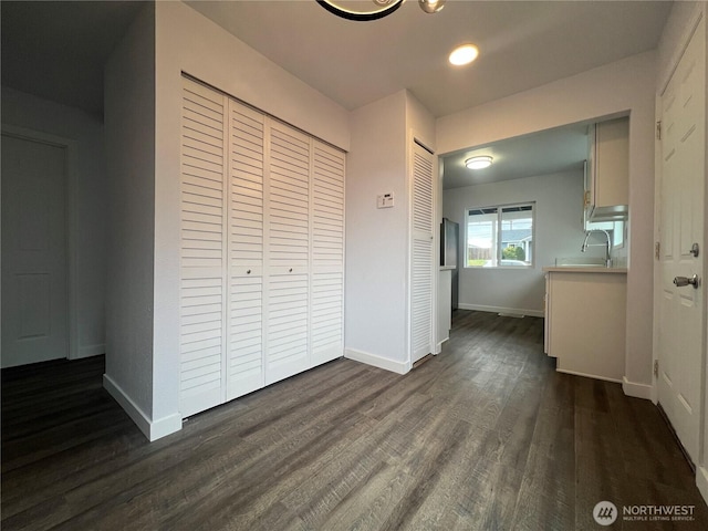 unfurnished bedroom with dark wood-style floors, baseboards, and a sink