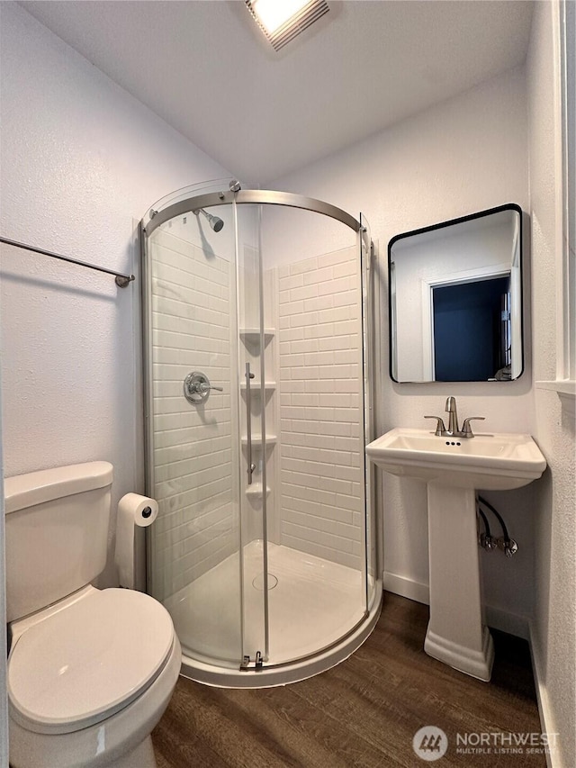 bathroom featuring visible vents, a shower stall, toilet, and wood finished floors