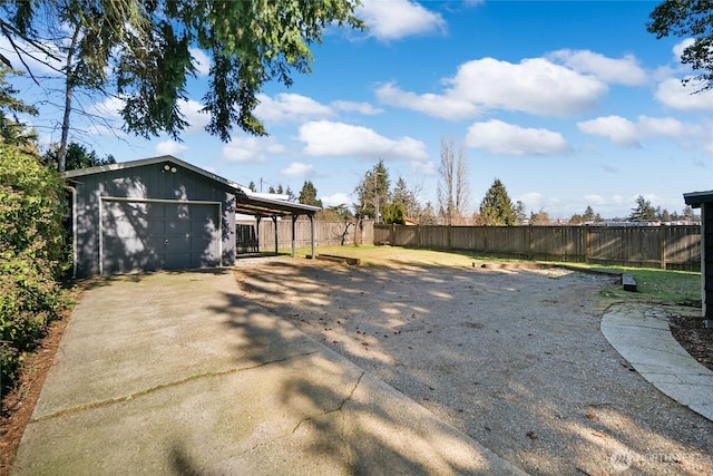 view of yard featuring an outbuilding, concrete driveway, and fence