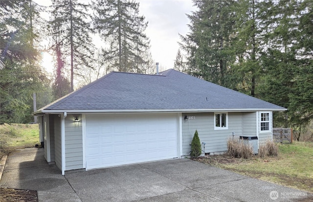 view of side of property with roof with shingles and a detached garage