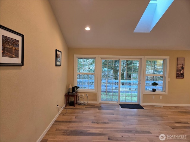 entryway with lofted ceiling with skylight, baseboards, wood finished floors, and recessed lighting