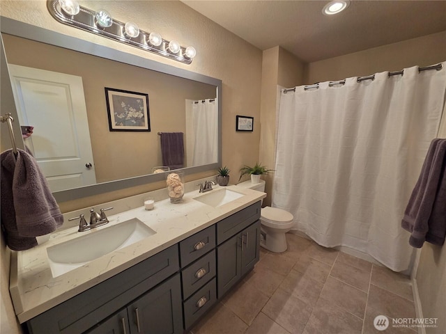 full bath featuring double vanity, tile patterned flooring, a sink, and toilet