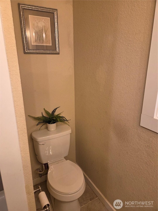 bathroom featuring tile patterned flooring, baseboards, and toilet