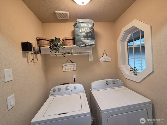 washroom with laundry area, visible vents, washer and clothes dryer, and a textured ceiling