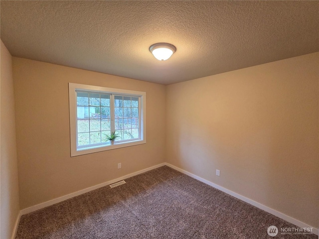 unfurnished room with baseboards, visible vents, dark carpet, and a textured ceiling