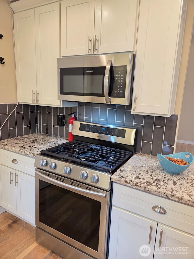 kitchen featuring light wood-style floors, tasteful backsplash, light stone counters, and stainless steel appliances