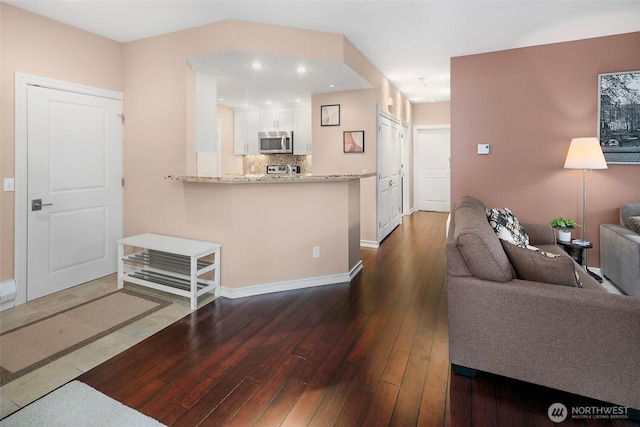 living room featuring dark wood-type flooring, recessed lighting, and baseboards