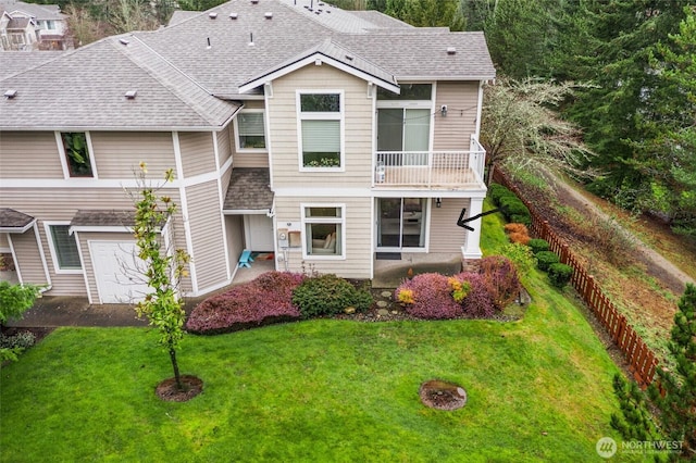 view of front of property featuring a balcony, a front lawn, and roof with shingles