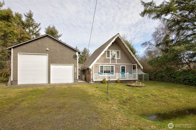 a-frame home with a porch, a front yard, a detached garage, and an outbuilding