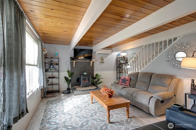 living area featuring wood ceiling, wainscoting, beam ceiling, plenty of natural light, and a wood stove