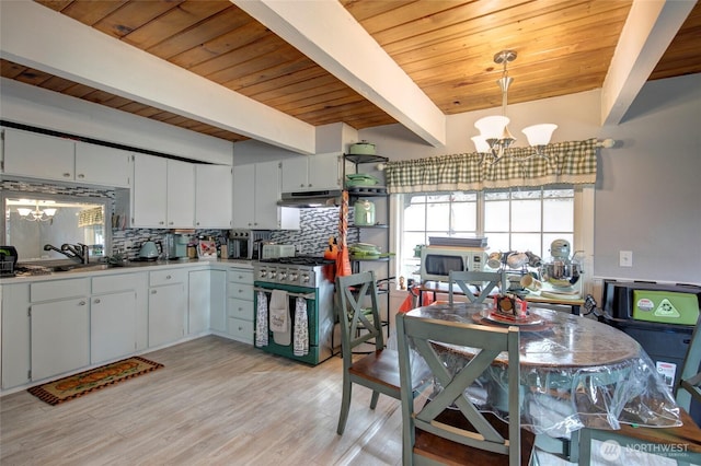 kitchen featuring a chandelier, white microwave, extractor fan, and stainless steel range with gas stovetop