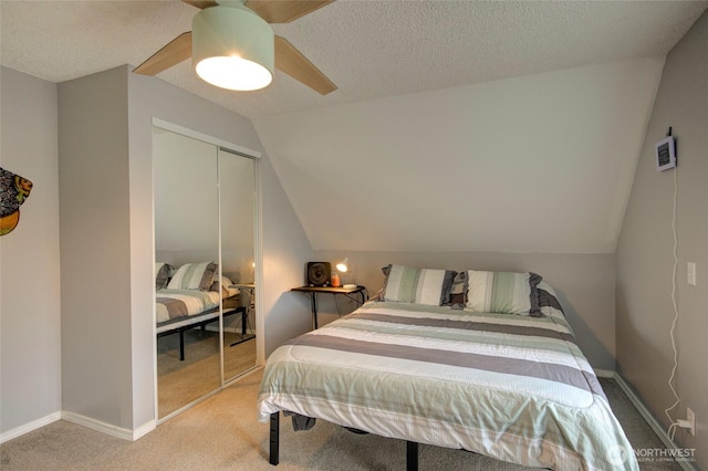 bedroom with a closet, carpet flooring, vaulted ceiling, and a textured ceiling