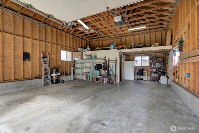 garage with a garage door opener and freestanding refrigerator