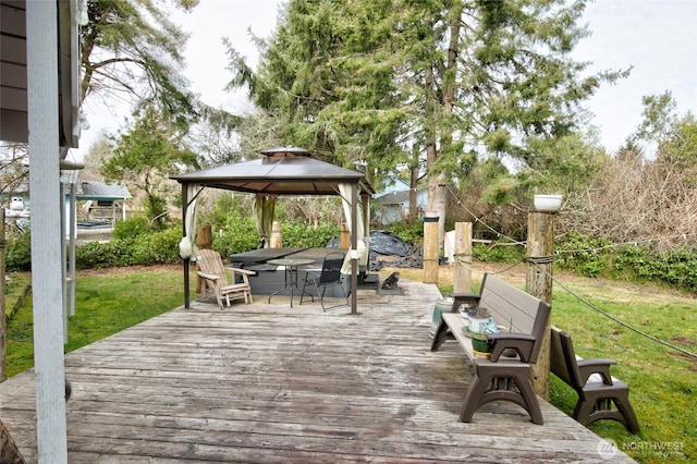 deck featuring outdoor dining space, a yard, and a gazebo