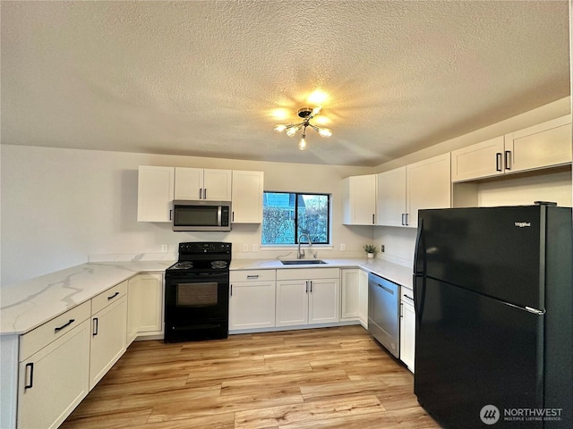 kitchen featuring white cabinets, light wood-style flooring, light stone counters, a peninsula, and black appliances