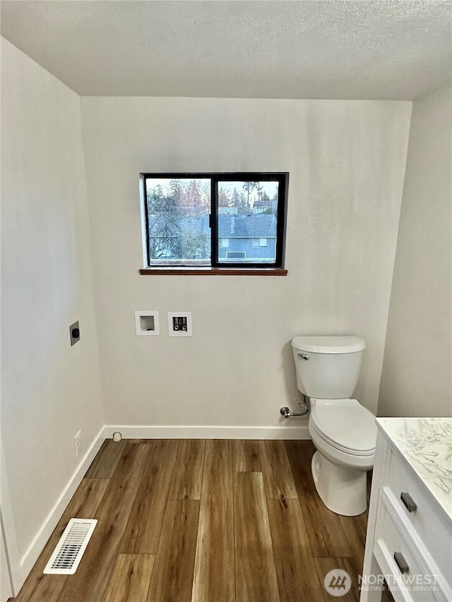 bathroom with visible vents, toilet, vanity, wood finished floors, and baseboards