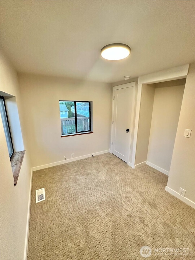 carpeted spare room featuring baseboards and visible vents